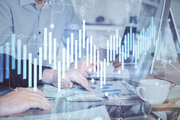 Multi exposure of chart with man typing on computer in office on background. Concept of hard work.
