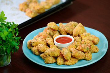 Fried crispy chicken nuggets with ketchup in a plate.