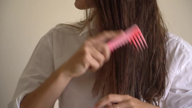 Woman with a comb in her hand brushing wet hair after bath