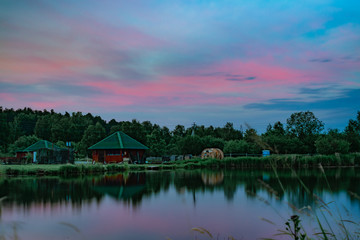 Long exposure scenic view of small red house on the bank of still pond