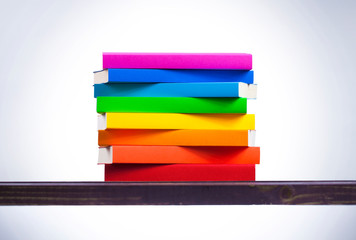 Stack of colored books on wooden table