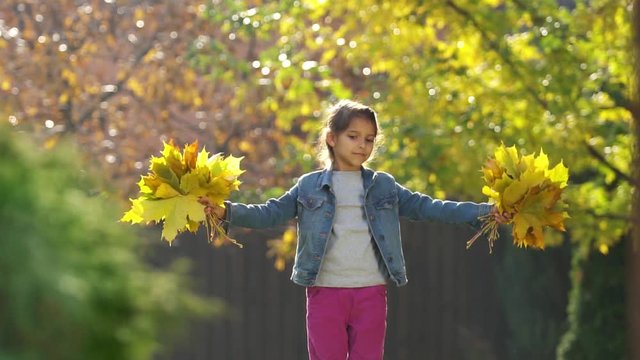 Girl on the outdoor is playing and rejoices with autumn leaves. 