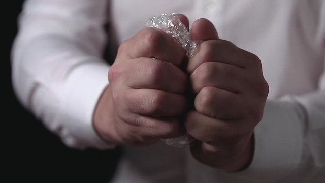 Male hands popping the bubbles in bubble wrap to relieve stress. Soothing therapy for nervousness or just for fun.