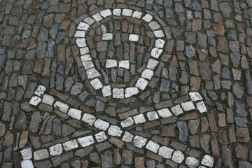 Skull and bones made with white stones in the cobblestone road.