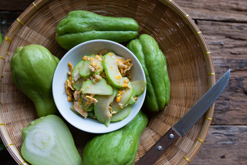 Fresh chayote fruits (Sechium edulis) stir fried with egg and garlic in bowl on wood background