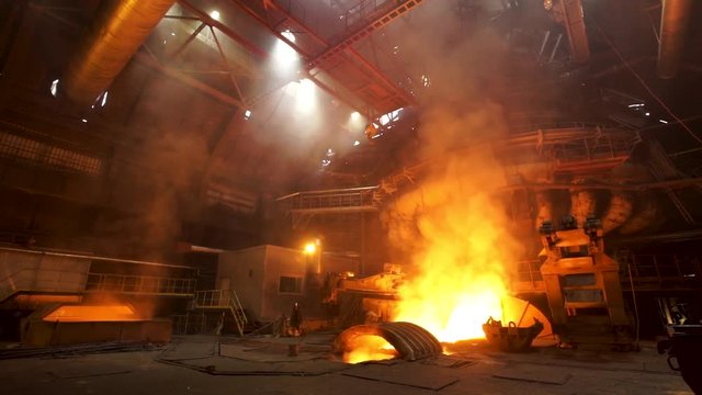 Close up for the electric furnace with melting metal and rising smoke. Stock footage. Metallurgical factory, release of steel in the foundry, heavy metallurgy concept.
