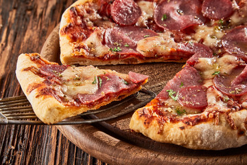 Serving a slice of Italian salami pizza