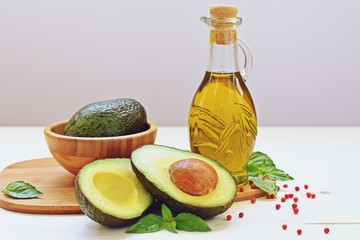 Close up of vegetarian food with avocado, limes and olive oil on white background. Front view, filter applied.