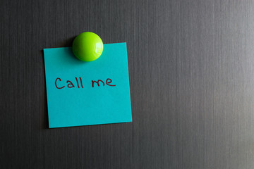 a note with the words call me magnet attached to the refrigerator.