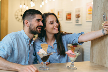 happy couple taking picture while eating ice cream indoor
