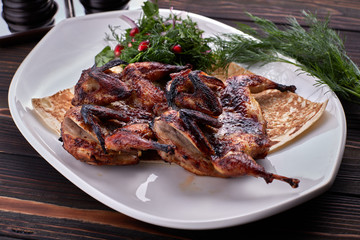 Fried quail on a plate on a wooden board
