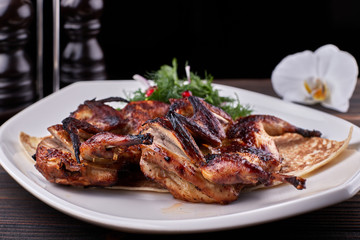 Fried quail on a plate on a wooden board