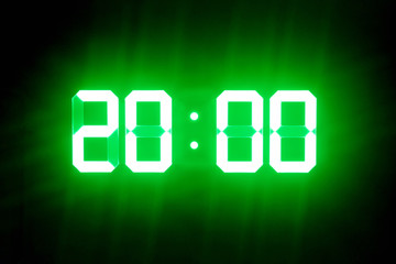 Green glowing digital clocks in the dark show 20:00 time