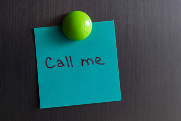a note with the words call me magnet attached to the refrigerator.