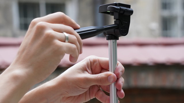 men's hands adjust the tripod to shoot video or photo. twist the height and angle adjustment knobs. photographer at work, details, backstage