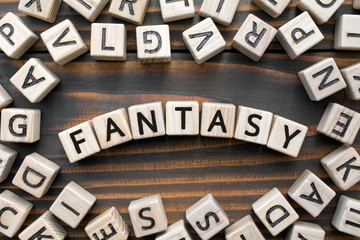 fantasy - word from wooden blocks with letters, Literary Genres concept, random letters around, top view on wooden background