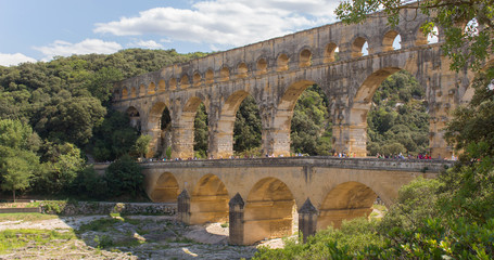 Pont du Gard is a Roman three-tiered aqueduct built in Provence (France) over the river Gardon. This view of the highest roman bridge in Europe is taken a sunny summer day. &ndash; Image