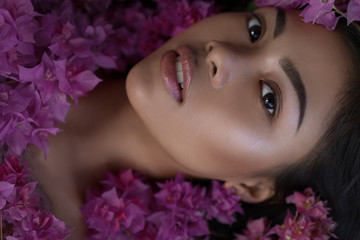 Asian girl portrait face in pink flowers. Beautiful Balinese women. Beauty salon and massage spa concept