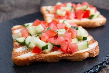 Vegetarian bread toast bruschettas with fresh cucumber and tomato.