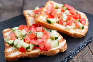 Vegetarian bread toast bruschettas with fresh cucumber and tomato.