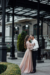 Beautiful couple near modern home. Young romantic couple embracing each other. Romantic moment. Man in suit and woman in dress.
