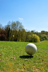  A golf ball on a golf course with flagstick