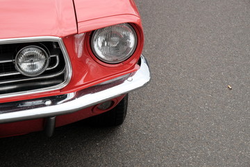 Frontpartie einer roten amerikanischen Sportwagen Ikone der Sechzigerjahre auf grauem Asphalt im...
