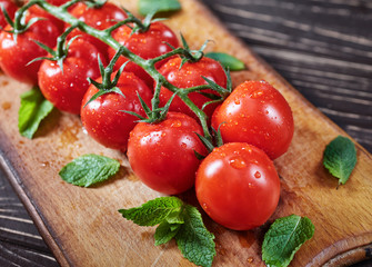 Drops of water on juicy tomatoes on a wooden board.