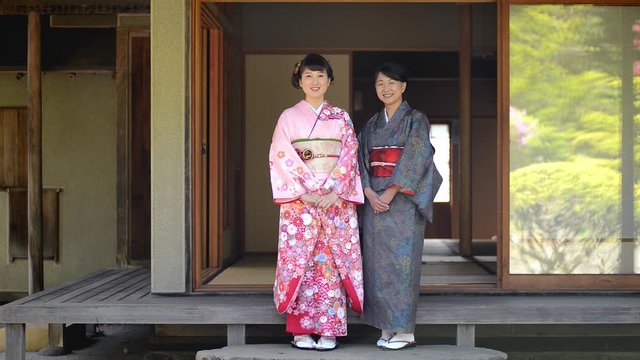 Two women in kimonos standing outside traditional Japanese house
