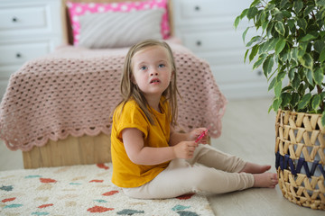 child with Down syndrome plays with toy scissors