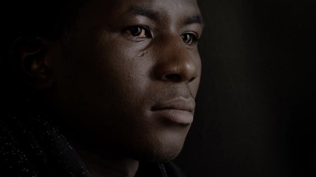 Pensive upset young black african man thinking in the dark
