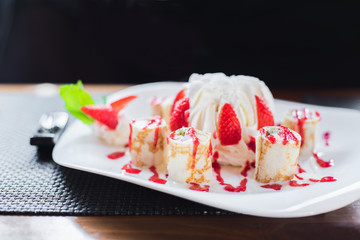 Dessert in a cafe. Dessert of cake with whipped cream, meringue, ice cream, decorated with fresh strawberries and mint. Rolls of dough with jam and cream.
