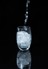 verre d'eau et gla&ccedil;ons  sur fond noir brillant