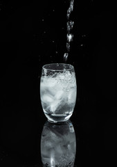 verre d'eau et glaçons  sur fond noir brillant