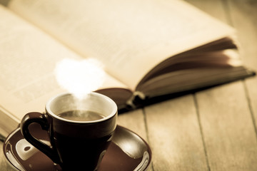 Cup of coffee with heart shape steam and open book