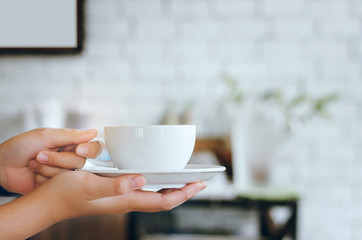 Closeup girl hands holding white cup of coffee served to customers