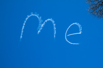 The word ME written large in a bright blue sky by a sign writing plane.