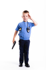 Cute little police boy with smile on face and gun on white background. Intelligent cool children in police suit with blue eyes and weapon. salute