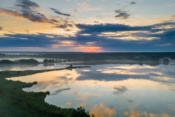 Naklejka premium Forest lake in the morning fog, in the rays of the dawn sun. Drone view.