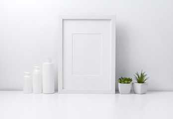 Mock up white frame, plants and cosmetic bottle containers on book shelf or desk.