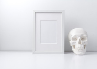 Fototapeta na wymiar Mock up white frame and skull on book shelf or desk
