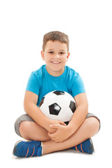 Smiling boy is holding a football ball made of genuine leather. Sitting on floor. Isolated on a white background. Soccer ball