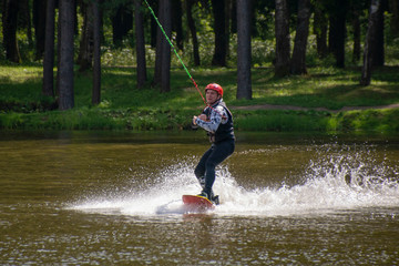 A young athlete dissects the water surface on a wakeboarding smooth Board