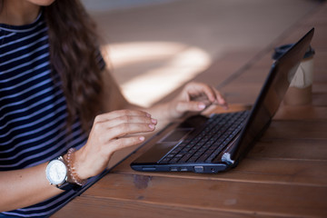 Neat young female hands without manicure, with large wrist watches, work at a laptop, standing on a...