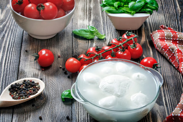 Mozzarella cheese, basil, cherry tomatoes, peppers, olive oil on a wooden table. Focus concept