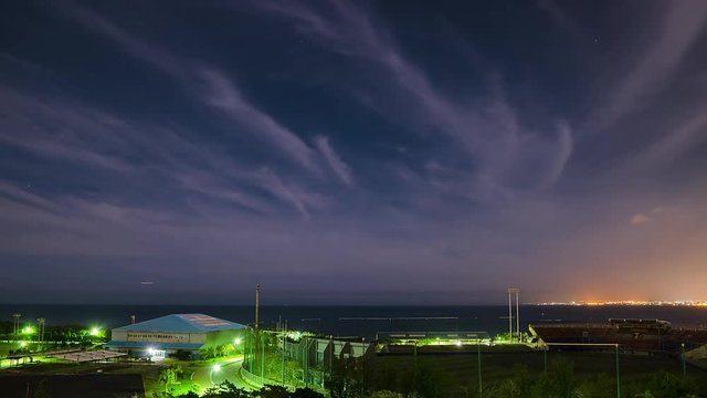Timelapse of clouds over coastal city at night, Okinawa, Japan