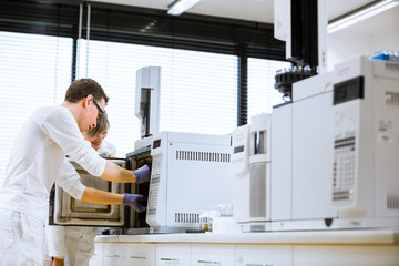 senior male researcher carrying out scientific research in a lab using a gas chromatograph (shallow DOF; color toned image)