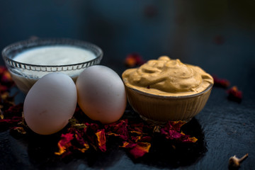 Best DIY face mask of multani mitti or mulpani mitti along with egg white and some yogurt well mixed in a glass bowl on the black wooden surface for the remedy of even skin.