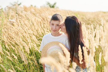 Family Summer vacation traveling in summer.Holidays in village. Outdoor lifestyle. Freedom concept. Woman in summer field. Mother and child son in wheat field.Children Protection and mothers Day