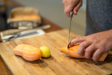 Süsskartoffeln mit großem Küchenmesser schneiden, Nahaufnahme Hönde eines Mannes